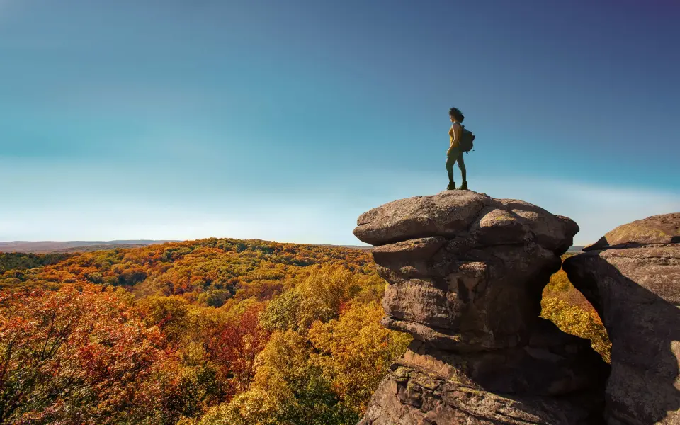 A hiker at the top of the garden of the gods in fall.